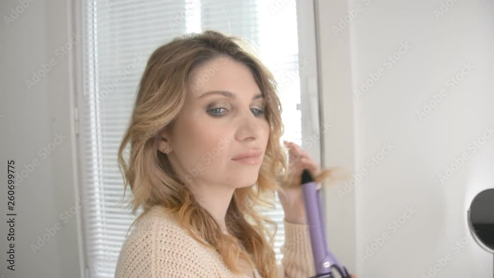Pretty woman face using hair tongs for curling hd footage Pretty woman face using hair tongs for curling hd footage