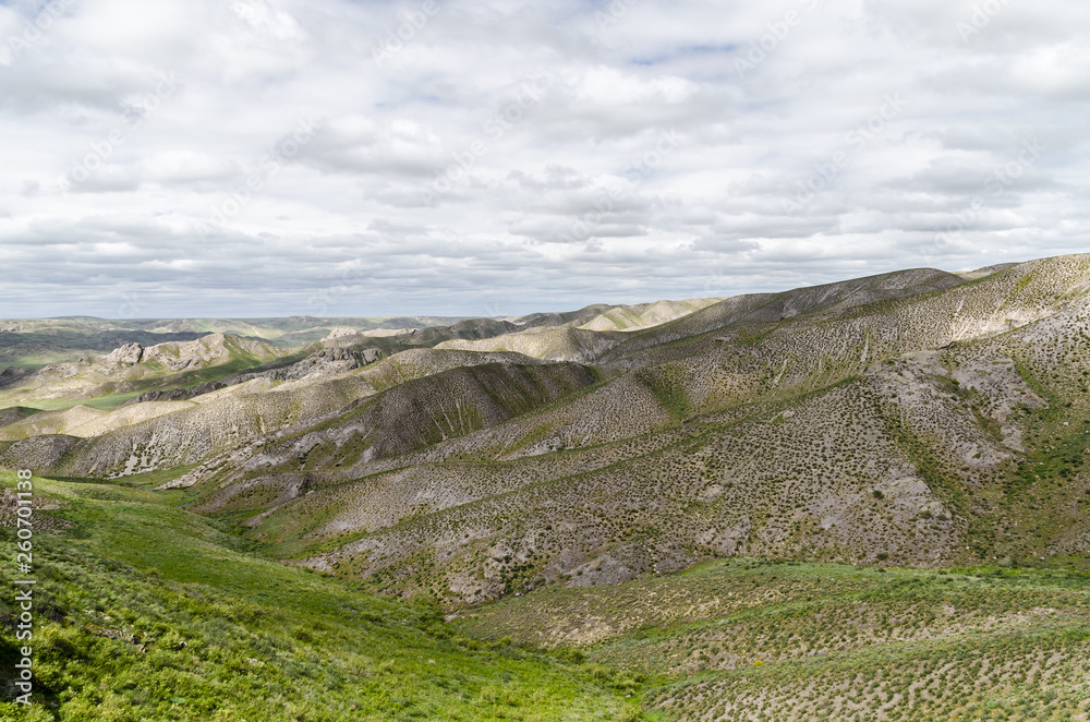 Steep and stony mountains in Kazakhstan, covered with green grass, sand and small stones Steep and stony mountains in Kazakhstan, covered with green grass, sand and small stones