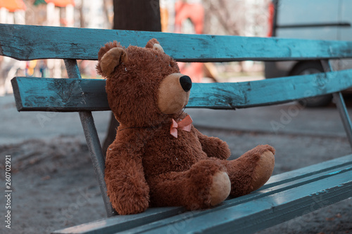 Abandoned teddy bear sitting on a bench.