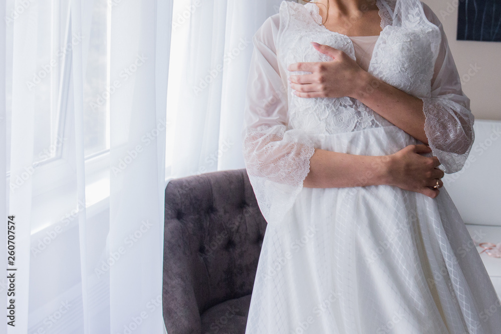 bride in peignoir holding a wedding dress