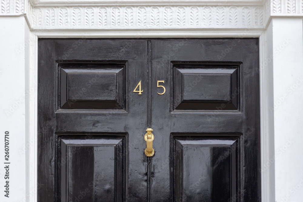 House number 45 with the forty five in bronze on a black wooden door with white door frame