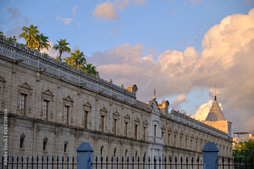 Fototapeta premium view of the Old Hospital of the Five Wounds at sunset with palms tree - Seville Spain.