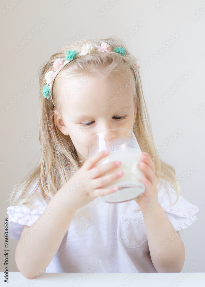 Little blond girl drink a glass of milk with different emotions, indoor, healthy food concept Little blond girl drink a glass of milk with different emotions, indoor, healthy food concept