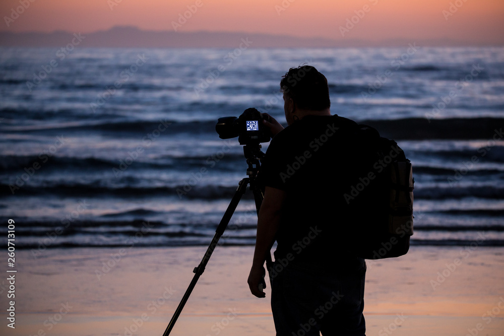 Ocean beach phographer silhouette during orange sunset west coast