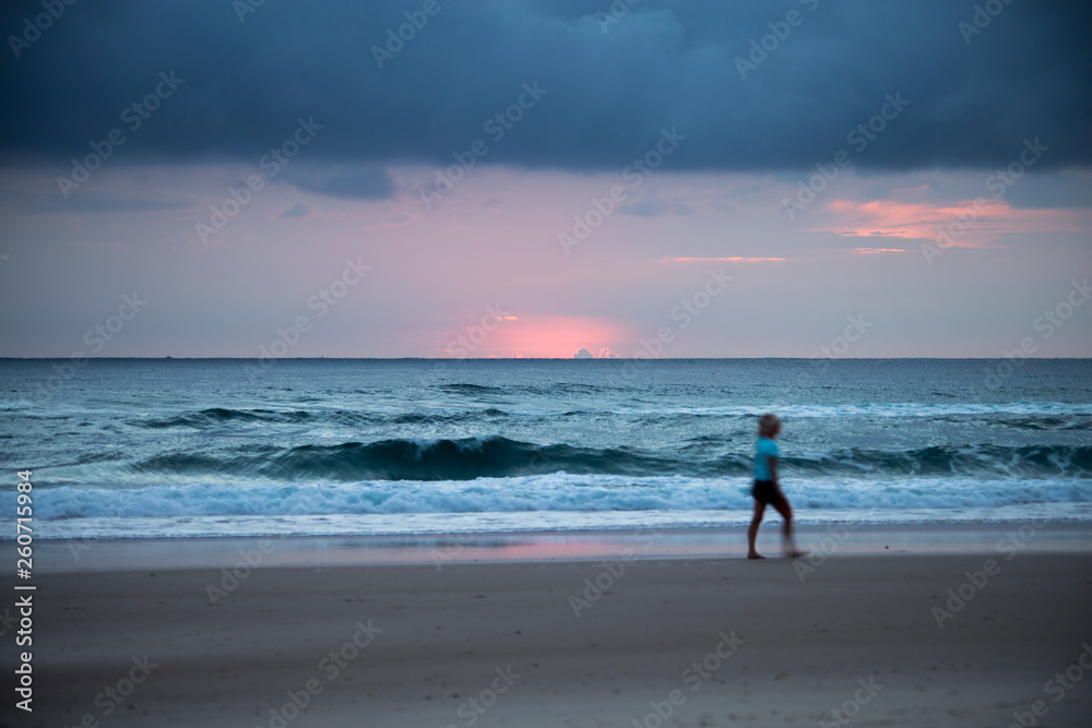 Woman walking on the beach at sunrise Woman walking on the beach at sunrise