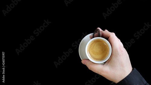Male hand holding a coffee cup. Close up of a hand of man holding a warm mug with fresh coffee isolated on black background. Coffee concept photo