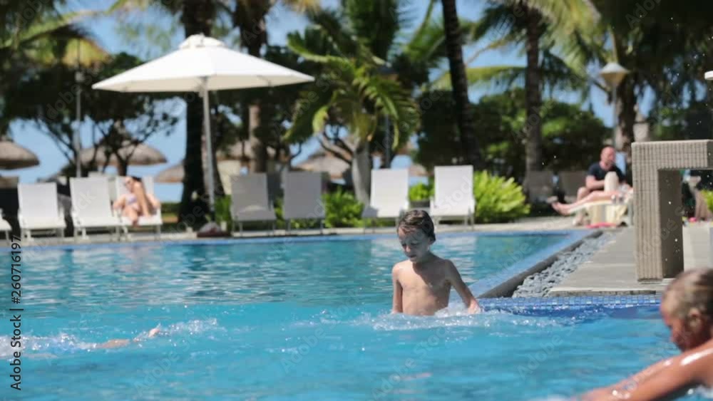 Happy children, brothers, having fun in the pool next to the beach in Mauritius Happy children, brothers, having fun in the pool next to the beach in Mauritius