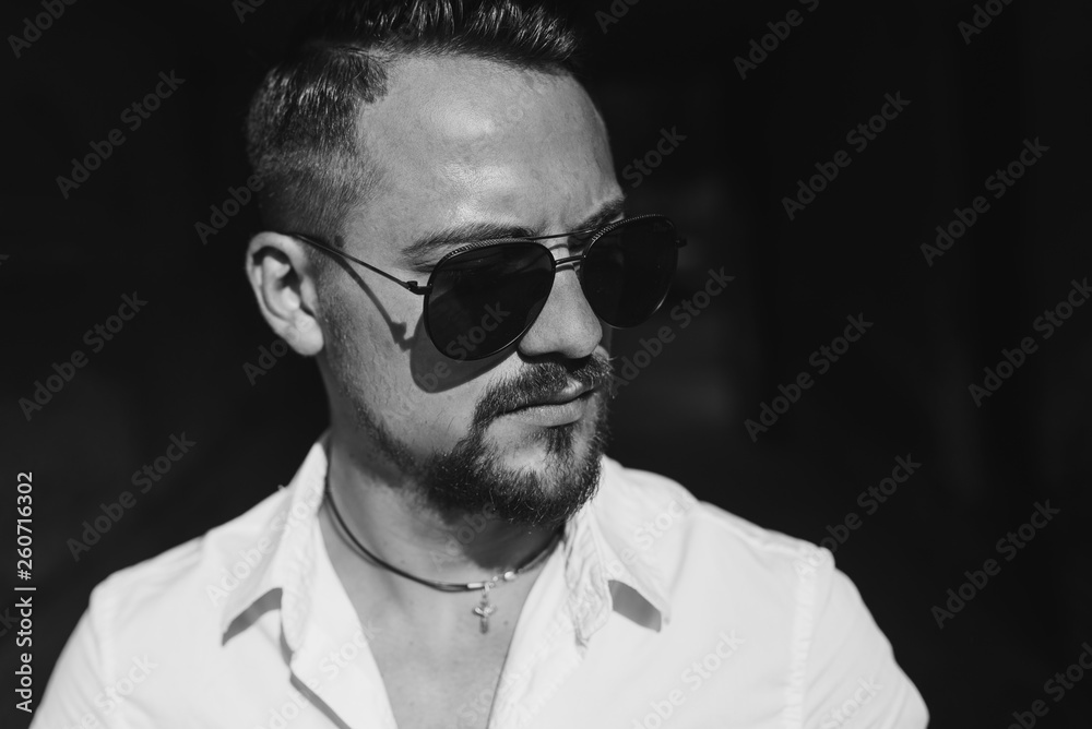 Portrait close up of handsome young businessman. Man dressed in white shirt and sunglasses on the grunge background. Black and white Portrait close up of handsome young businessman. Man dressed in white shirt and sunglasses on the grunge background. Black and white