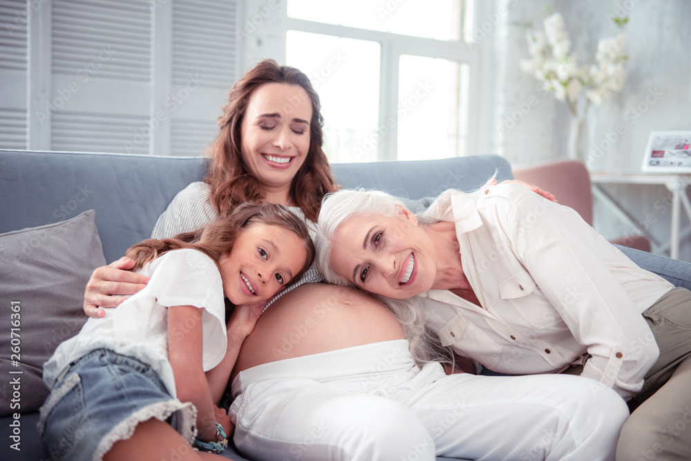 Woman laughing while daughter and mother listening to tummy