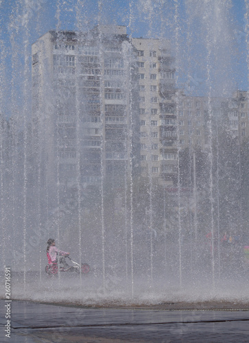 .....in the shadow of the fountain rides a little girl on a bicycle	