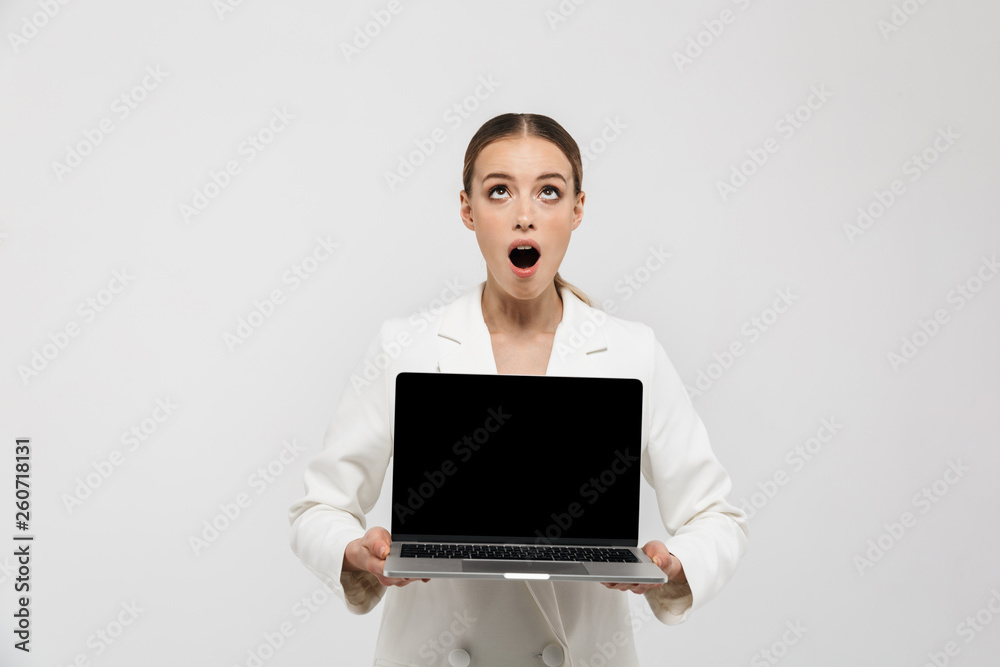 Photo of happy businesswoman 20s wearing elegant jacket holding laptop and showing black screen