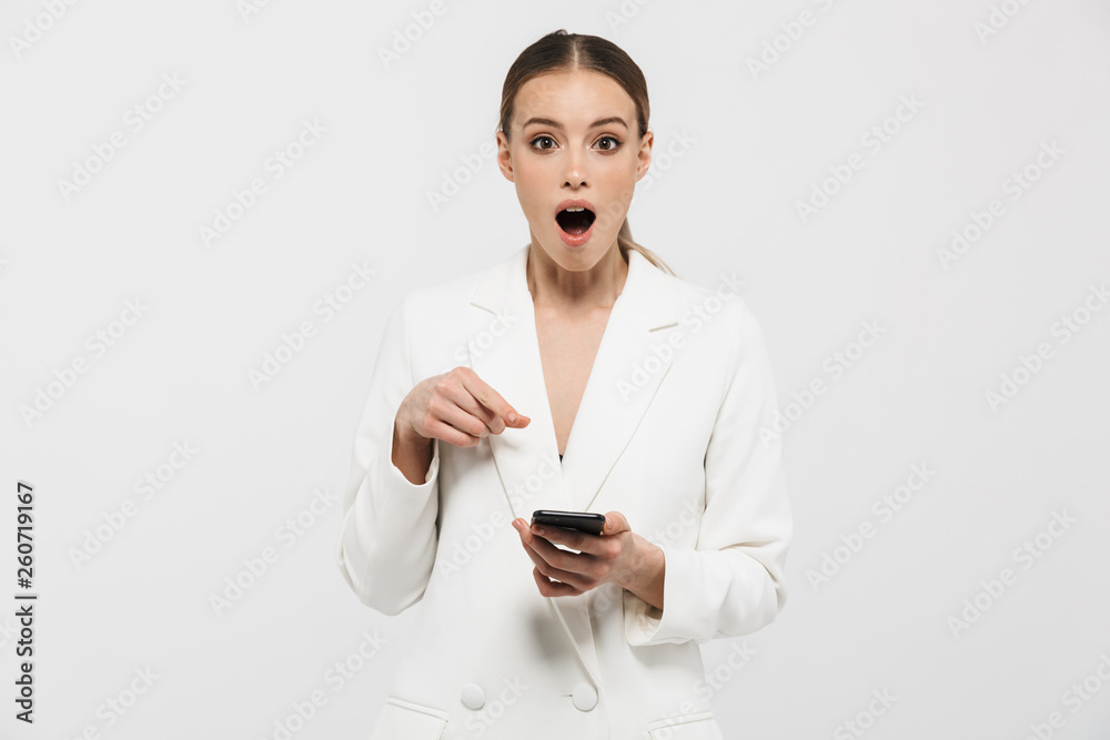 Photo of excited businesswoman 20s wearing elegant jacket holding and showing on cell phone screen