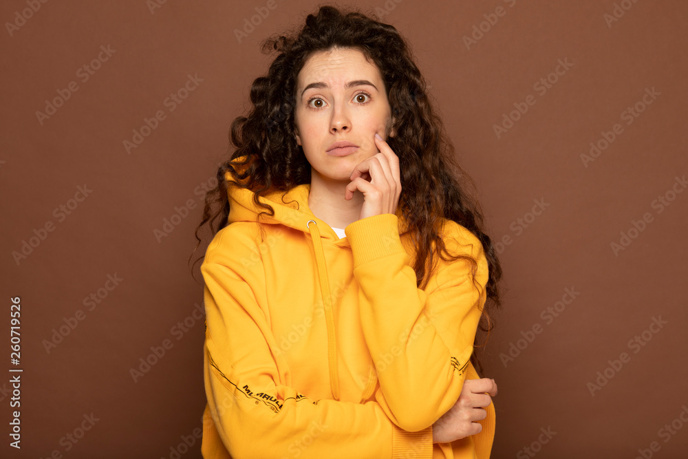 Thoughtful model in studio looking away. hand near the face. isolated brown background Thoughtful model in studio looking away. hand near the face. isolated brown background