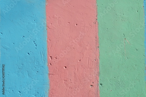 Fragment of bright painted concrete plastered wall. Striped rainbow background. Rough wall texture