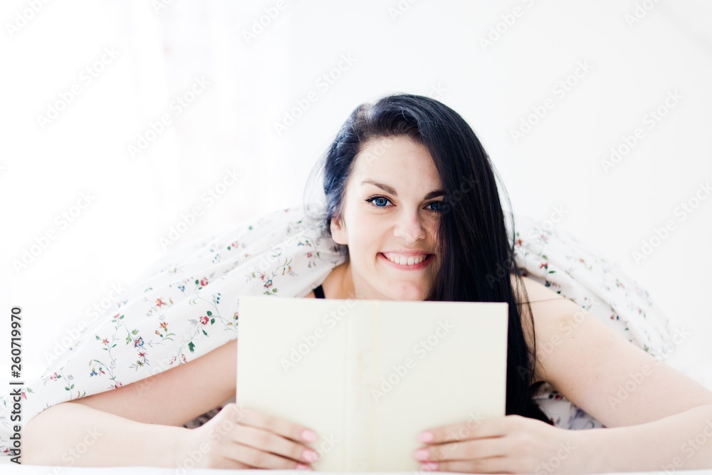 Attractive woman smiling, relaxing and reading book in bedroom Attractive woman smiling, relaxing and reading book in bedroom