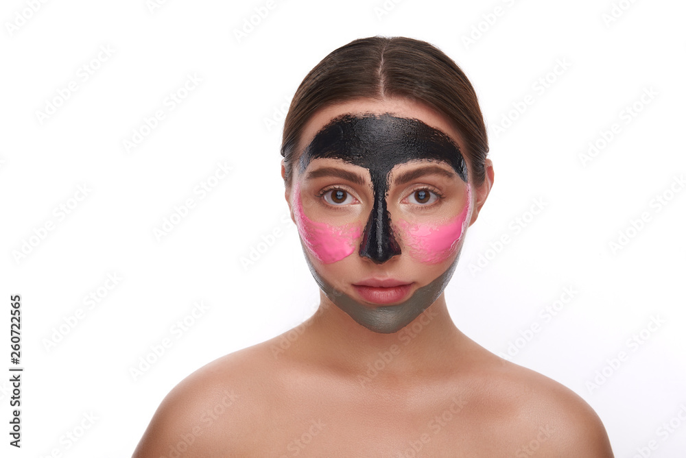 Young woman using colorful facial mask and looking at the camera
