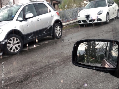 Car mirror and window during rainy day and the cars on the road 