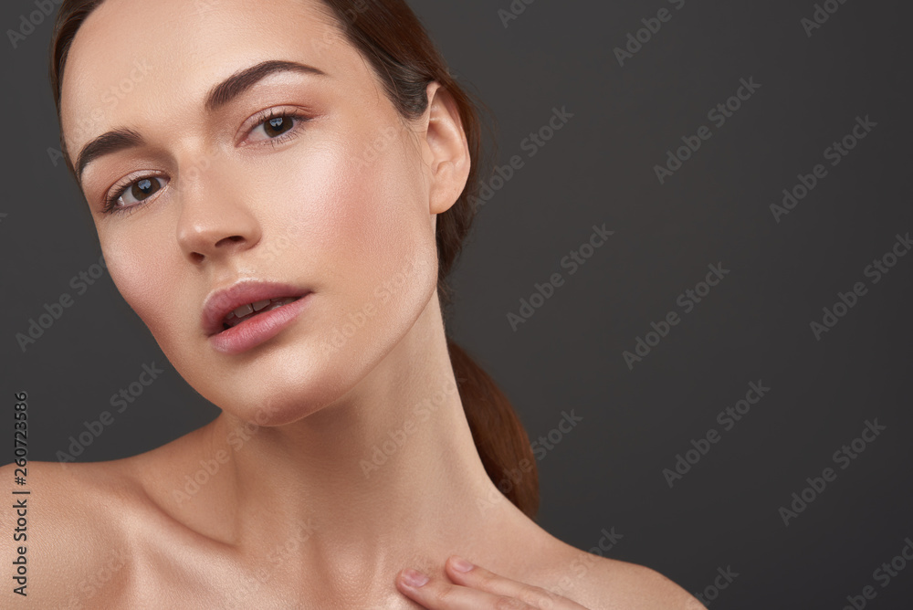 Charming young woman with natural makeup posing against gray background Charming young woman with natural makeup posing against gray background