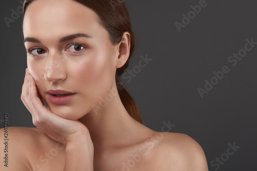 Beautiful young woman with perfect skin resting her chin on hand