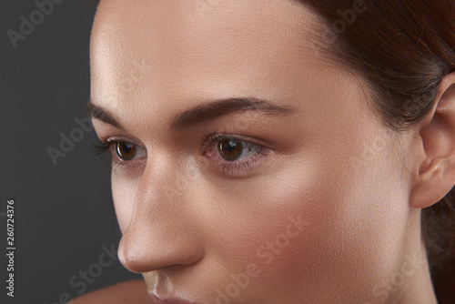 Young woman with beautiful brown eyes posing against gray background