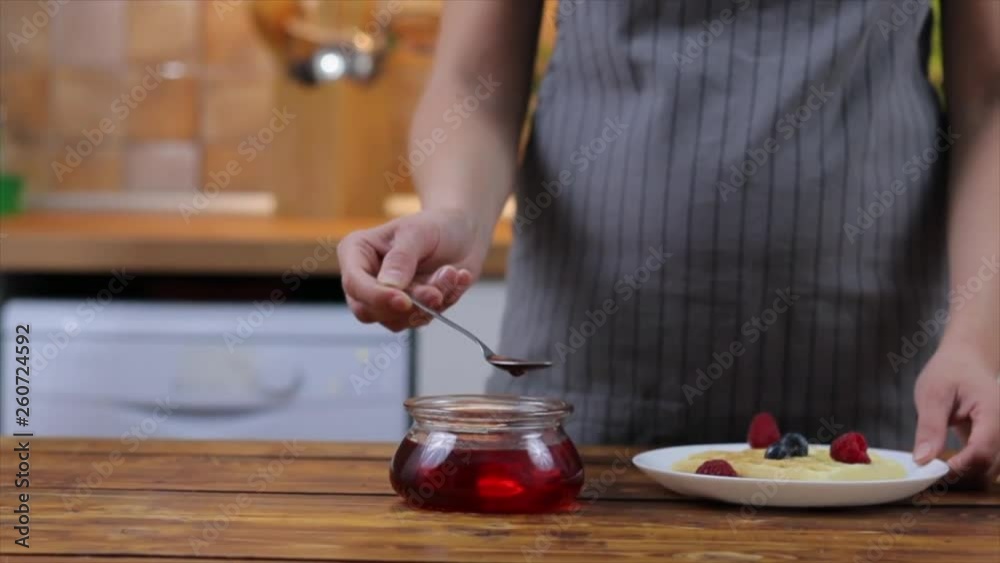 Woman pouring straberry sauce onto tasty homemade waffles, closeup Woman pouring straberry sauce onto tasty homemade waffles, closeup