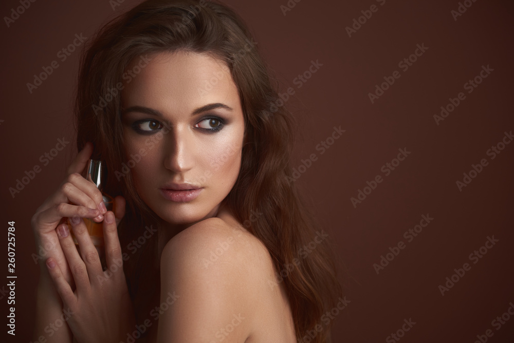 Attractive young woman with smokey eyes makeup holding perfume Attractive young woman with smokey eyes makeup holding perfume