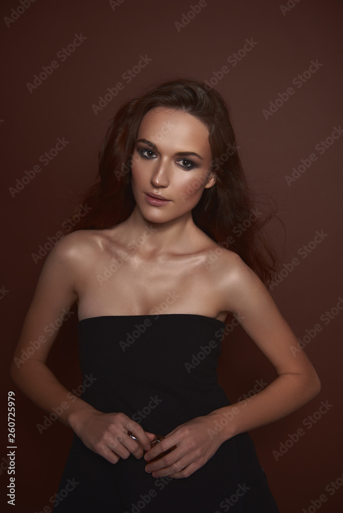 Beautiful young woman in elegant black dress holding perfume Beautiful young woman in elegant black dress holding perfume