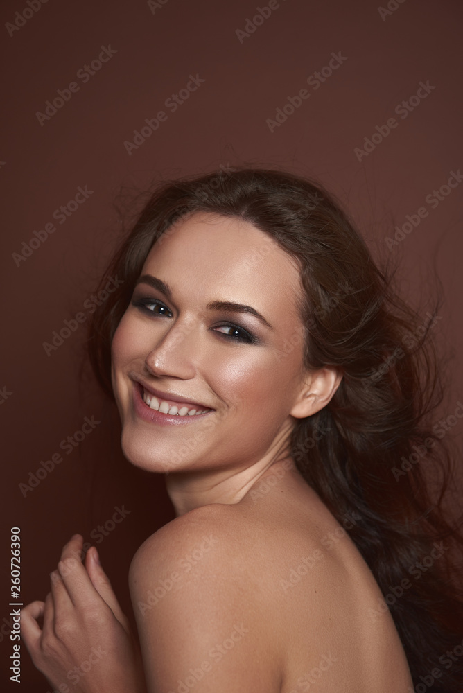 Fototapeta premium Radosna ładna pani pozowanie na brązowym tle