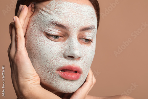 Serious woman pulling her skin on the face and looking down