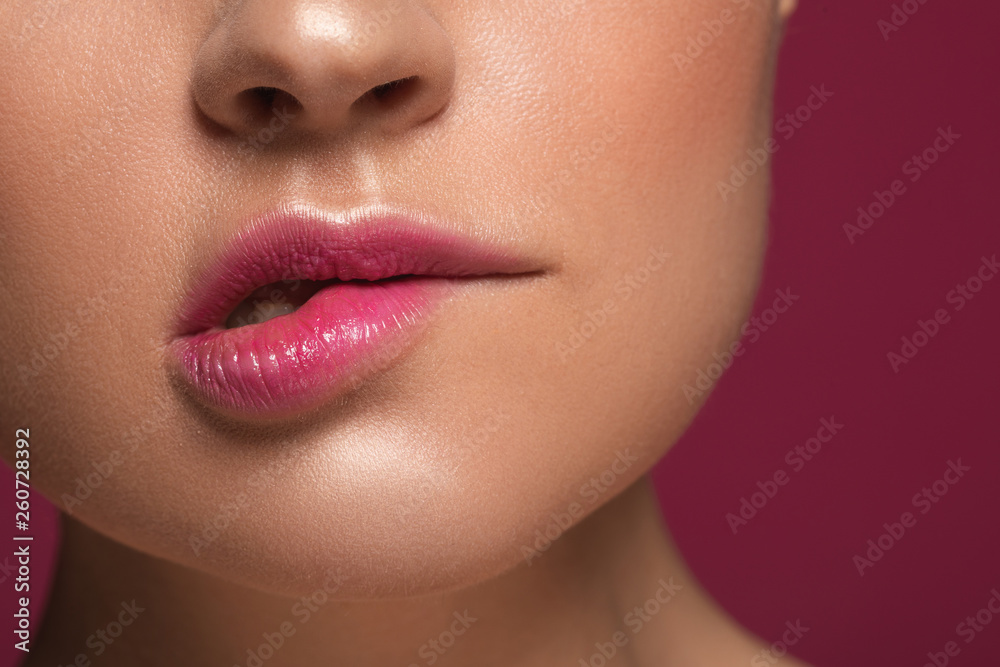 Woman biting her lip isolated on the maroon background Woman biting her lip isolated on the maroon background
