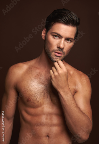 Handsome naked muscular man posing on camera