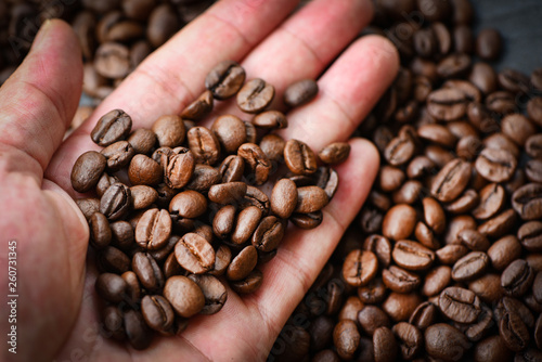 Coffee beans in hand and coffee bean roasted on background