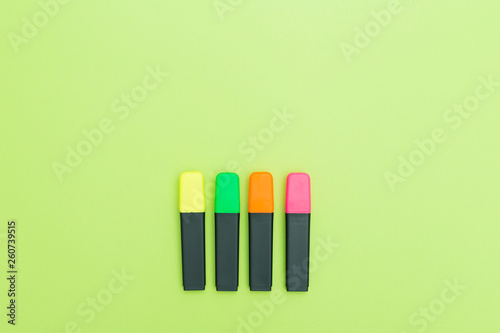 Colorful text markers on greenbackground. Copy space. Flatlay.