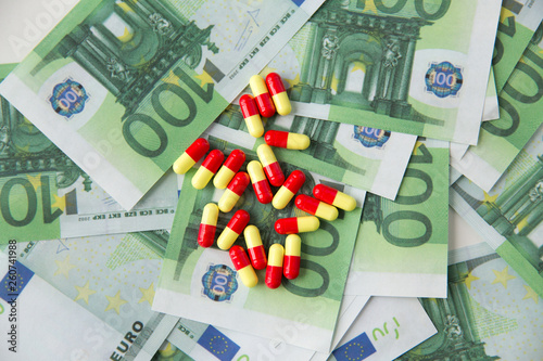 medicine, healthcare and drug trafficking concept - close up of medical pills or drugs and euro cash money