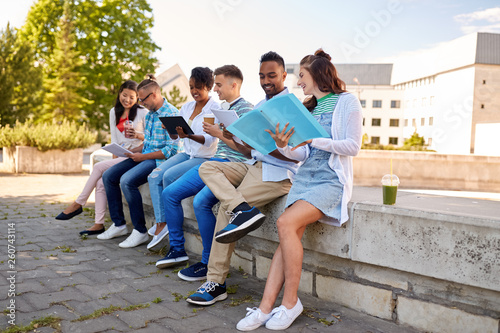 education and people concept - group of happy students with notebooks, tablet computer and takeaway drinks learning outdoors