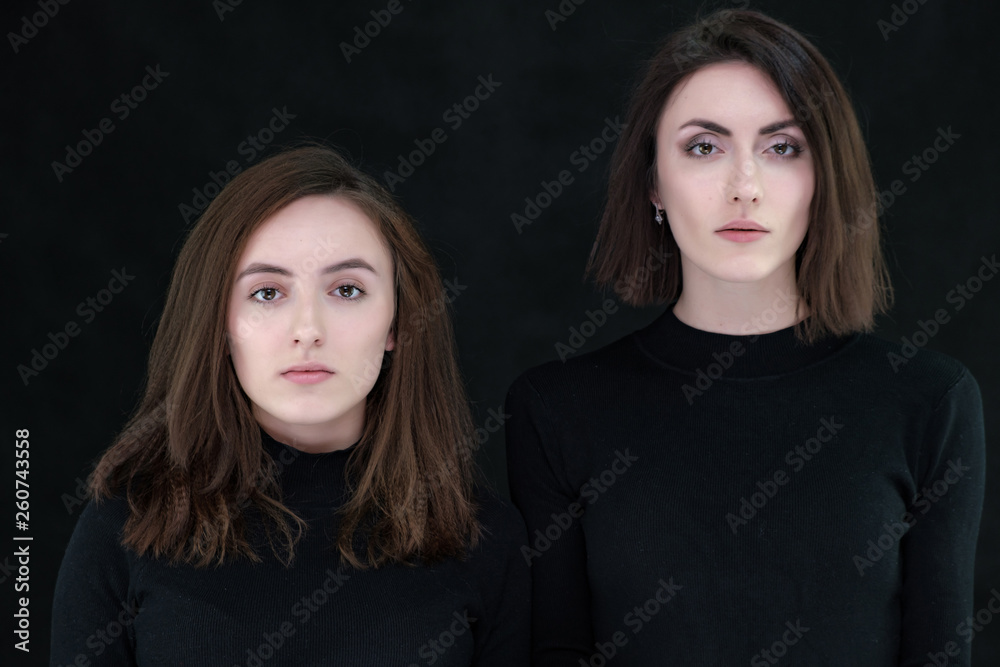 Concept portrait of two stylish brunette sisters on a black background in various poses. Fashionable photo of two beautiful girls with dark hair Concept portrait of two stylish brunette sisters on a black background in various poses. Fashionable photo of two beautiful girls with dark hair