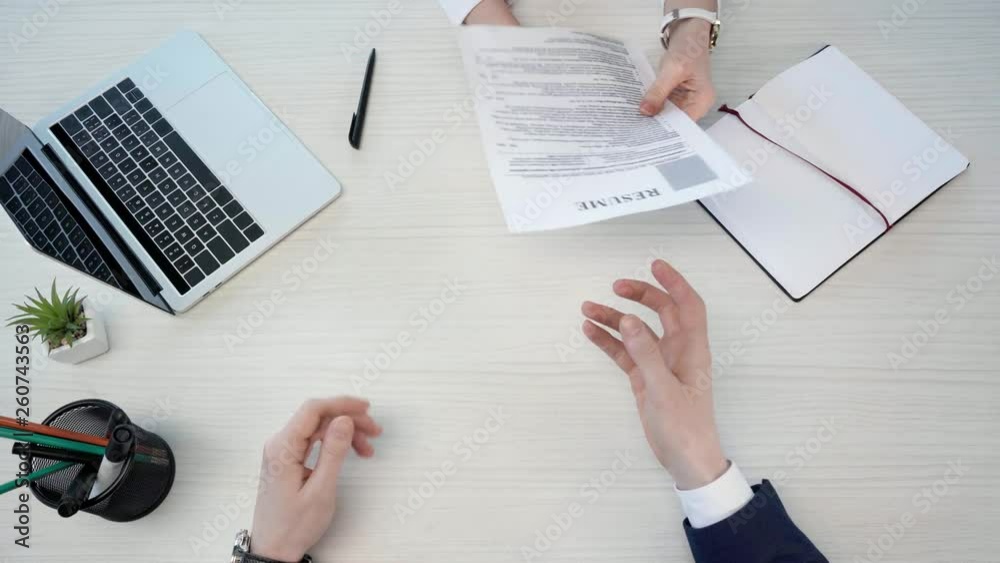 top view of man giving resume and leaving, while woman near blank notebook and laptop, throwing crumpled paper