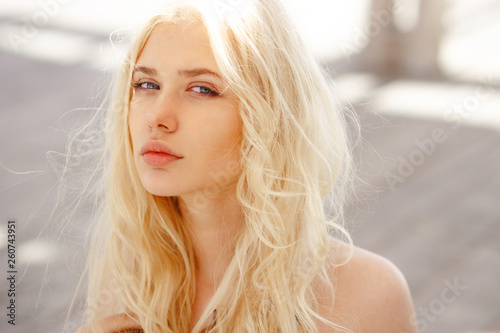 Cute blonde with angelic blue eyes,curl hair and big lips look innocent at camera, isoalted on a wooden floor.