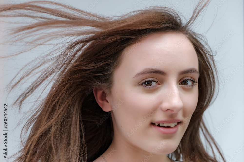 Conceptual portrait of a stylish brunette girl on a white background with flowing hair. Fashionable photo of beautiful girl with dark hair Conceptual portrait of a stylish brunette girl on a white background with flowing hair. Fashionable photo of beautiful girl with dark hair
