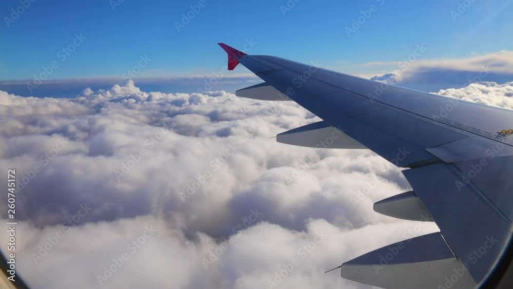 Wing of an airplane flying above the sky with clouds Wing of an airplane flying above the sky with clouds