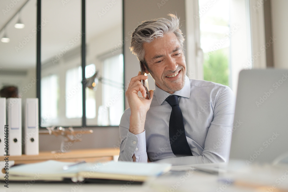 Businessman talking on cellphone in contemporary office Businessman talking on cellphone in contemporary office