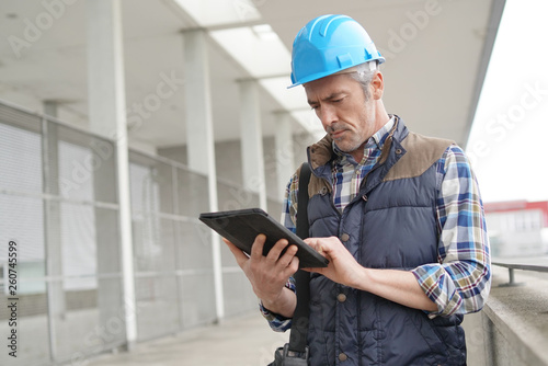 Lead architect checking tablet outside contemporary building