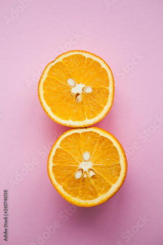 Two halfs of oranges on the pink background