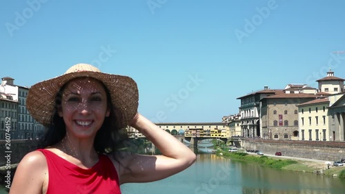 Cheerful woman making heart symbol with hands near Ponte Vecchio, Florence, Tuscany, Italy. Happy traveler showing loving shape for old bridge, love sign, beautiful attraction and tourism destination