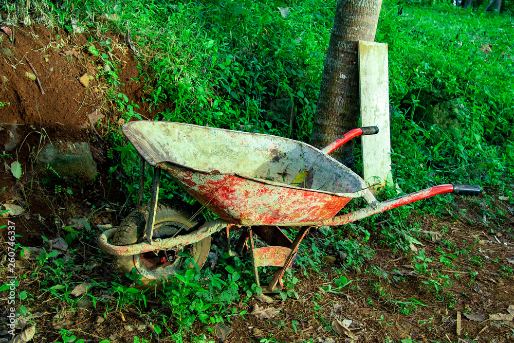 abandoned wheelBarrow in wet soil and grassy, dirty and rusty wheelBarrow abandoned wheelBarrow in wet soil and grassy, dirty and rusty wheelBarrow