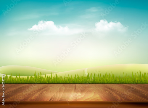 Nature background with wooden deck in front of green grass and blue sky,