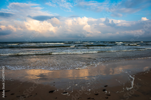 empty sea beach before storm with dramatic clouds and shadows from trees on the sand