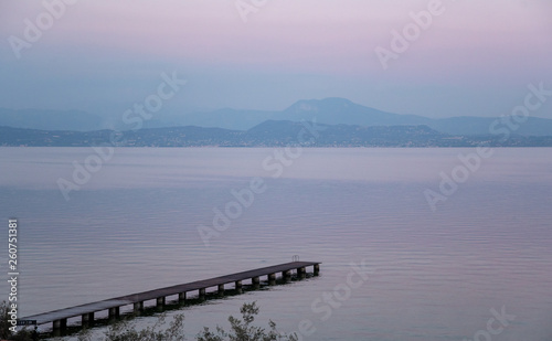 High angle view of Lake Garda with a pier and the mountainous coast on the horizon at sunset, Sirmione, Lombardy, Italy