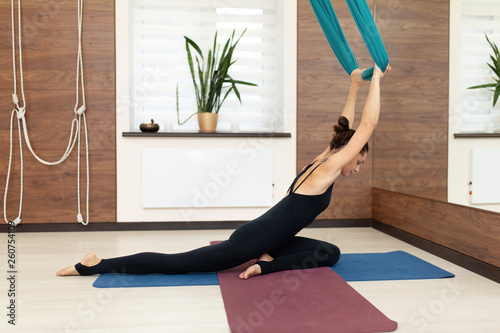 Woman doing fly yoga stretching exercises in gym. Fit and wellness lifestyle photo