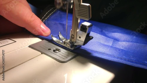 Person stitches cloth on the sewing machine. Cratches the thread on the fabric. photo